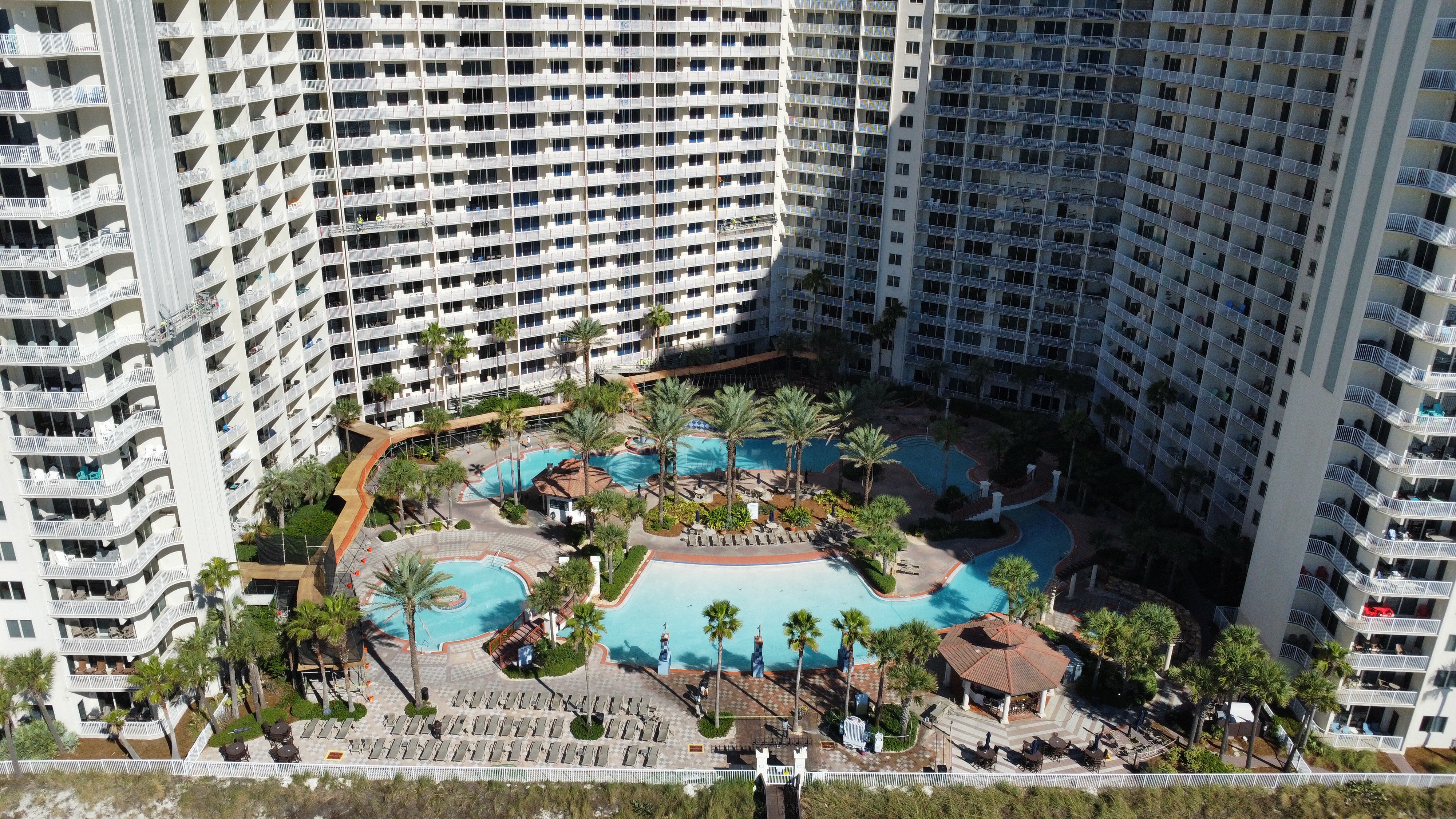 Aerial view of a coastal resort community with pools and balconies.