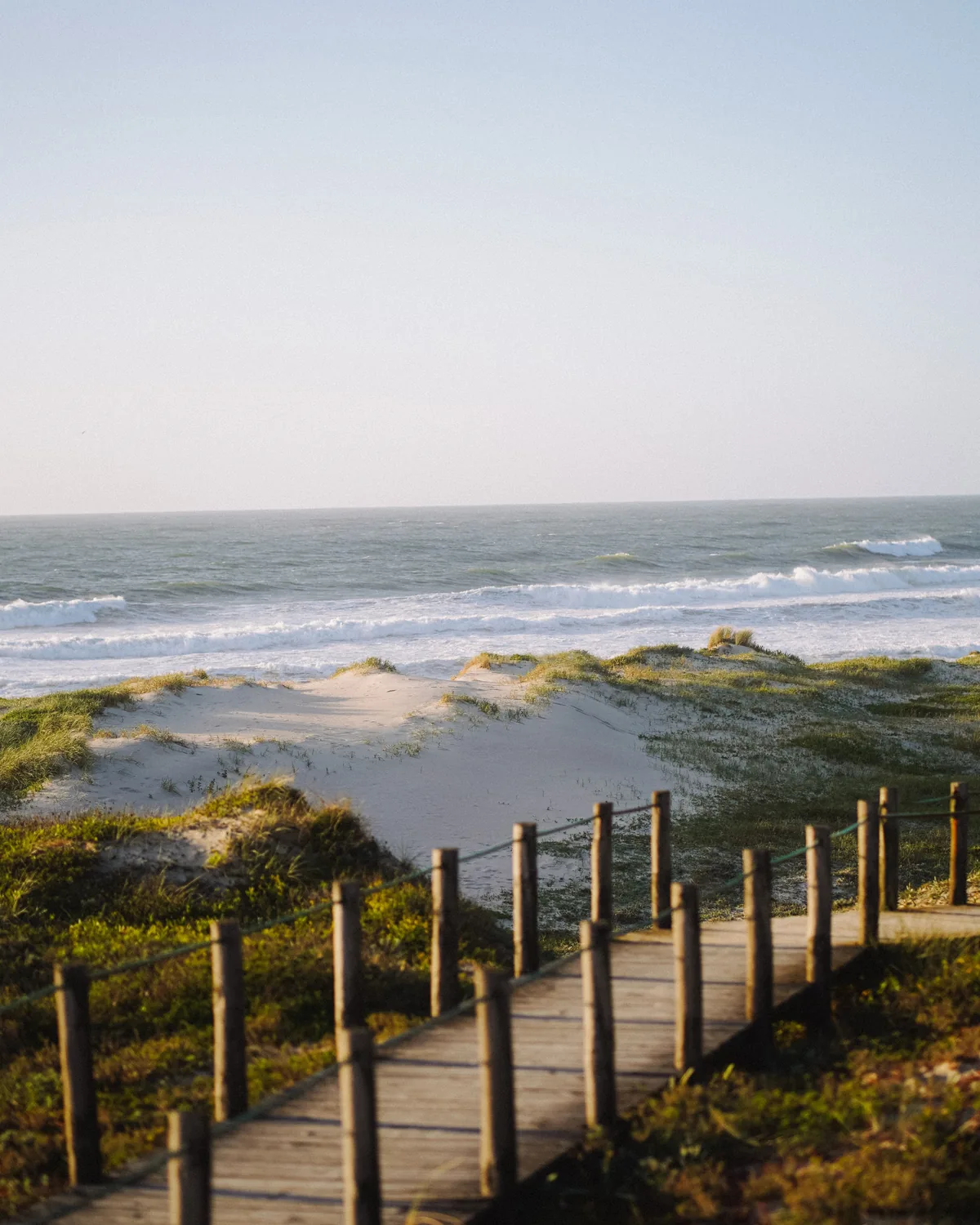 Wooden boardwalk crossing coastal dunes toward the beach.